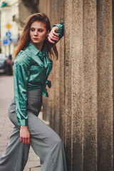 Fashion shooting. Wide trousers tube. Satin emerald blouse. Fashion trend. Tall brunette model.