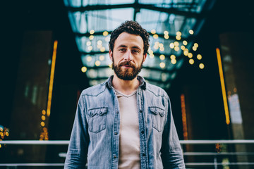 Half length portrait of handsome bearded young man with beard dressed in casual wear looking at...