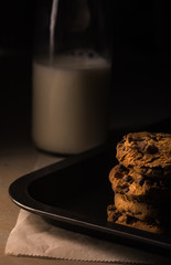 Several American cookies on a tray and a bottle of milk.