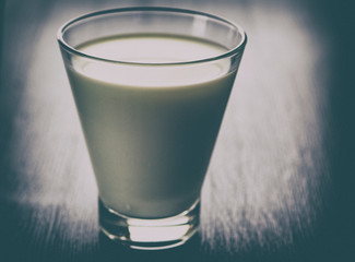 Milk in a glass cup on a wooden background. Photographed close-up in a low key.