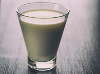 Milk in a glass cup on a wooden background. Photographed close-up in a low key.