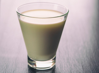 Milk in a glass cup on a wooden background. Photographed close-up in a low key.