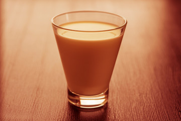 Milk in a glass cup on a wooden background. Photographed close-up in a low key.