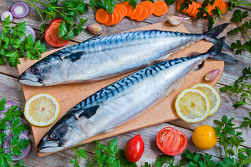 Fresh raw fish mackerel and ingredients for cooking on a wooden background