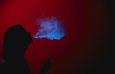 Girl silhuette smoking vape on a red background