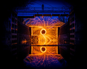 Light painting photography in a river lock with bridge