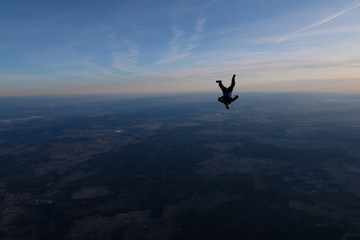 Skydiving. A solo skydiver is in the sunset sky.