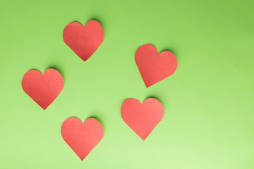 Five paper hearts on a green background. Text space
