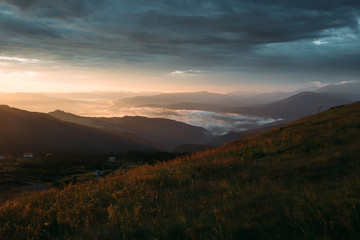Fototapeta premium Sunrise in the cloudy sky, fog descended on the mountains and hills