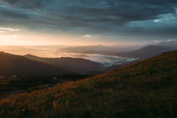 Sunrise in the cloudy sky, fog descended on the mountains and hills