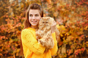 portrait of young woman in autumn park with cat