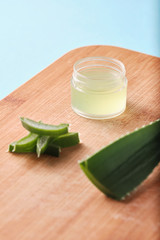 Obraz na płótnie Canvas aloe vera slices and balm box, aloe vera leaf on cream on bamboo cutting surface