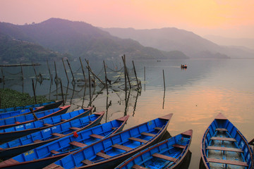 Pokhara, Nepal - March 12, 2014: The calm and quiet Lake Feva at sunset is the main attraction of the city of Pokhara. Simple wooden fishing boats are tied to the shore.