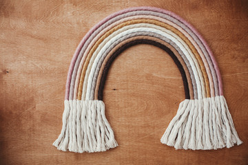 Stylish macrame rainbow decoration on wooden table. Modern boho   rope rainbow for baby room or...