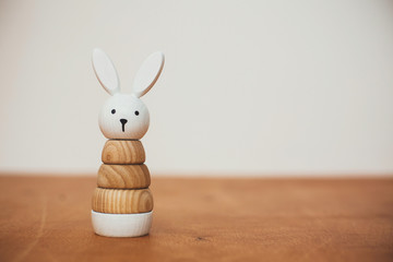 Stylish wooden toy for child on wooden table. Modern  wooden bunny pyramid with rings. Eco...