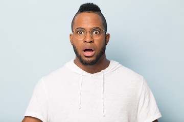 Shocked scared African American man in glasses looking at camera
