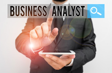 Writing note showing Business Analyst. Business concept for someone who analyzes an organization or business domain Male human wear formal work suit hold smartphone using hand