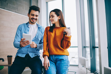 Positive hipster guys watching funny comedy video online via application on touch pad while spending leisure time togetherness, happy smiling male and female bloggers enjoying chatting with followers