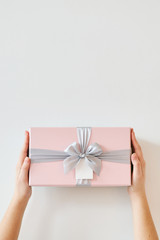 A girl holds a gift box on a white background. 