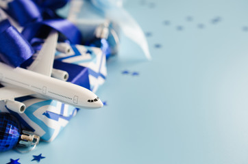 Christmas or New Year travel concept. Toy airplane with passports and gift boxes on blue background.