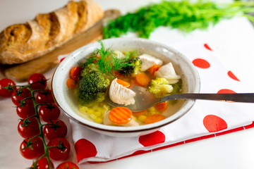 Homemade chicken vegetable soup, overhead, close-up view on a white background. bowl of fresh homemade soup to cure flu at table, top view. Vegetable soup with ingredients carrot cauliflower potato 