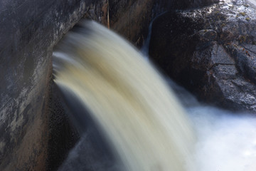 Powerful water pouring out of hole in concrete dam