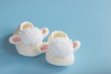 Close-up, knitted shoes for newborn on blue background