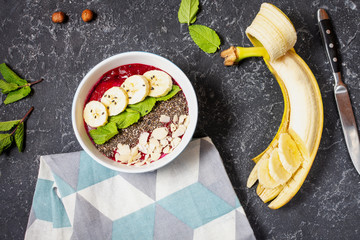 Healthy breakfast bowl: blueberry smoothie with banana, raspberry, almonds and chia seeds.