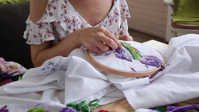 Female hands with vitiligo sewing with needle. embroidery hoop, embroidered fabric with colorful pattern, close up. Traditional hobby, lifestyle. Needlework, handicraft. young girl in summer dress sew