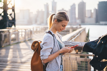 Side view of Caucasian female tourist with travel backpack checking location information while...