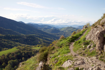 Autumn landscape. An uphill path overlooking a beautiful hilly valley and blue cloudy skies in the...
