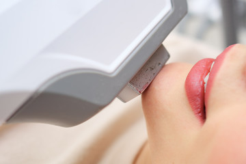 smiling girl client gets rid of excess hair with multi-functional device on laser therapy course selective focus