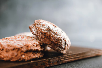 Homemade delicious chocolate cookies with powdered sugar on dark background, close-up view