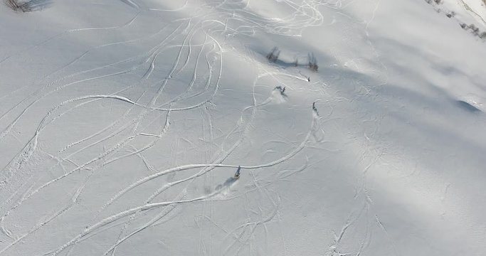 A group of extreme snowboarders are on the top of the high mountains with fresh snow in sunny winter day. Freeride on off piste slope. Top aerial view. Caucasus Mountains, Georgia, ski