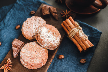 Homemade bakery, chocolate cookies with powdered sugar, cinnamon sticks, star anise on blue napkin