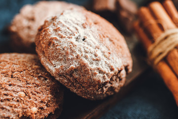 Homemade bakery, chocolate cookies with powdered sugar, cinnamon sticks, close-up view