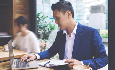 Focused ethnic businessman typing on laptop in cafe