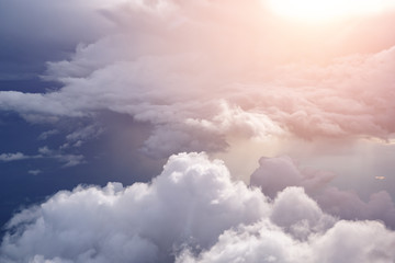 Aerial view from the plane of white soft fluffy clouds over the green landscape in sky in sunny...