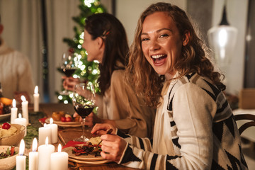 Photo of beautiful cheerful people eating while having Christmas dinner