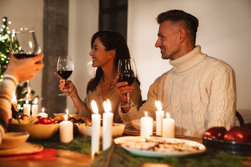 Photo of beautiful happy people drinking wine while having dinner