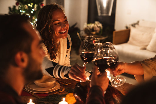 Photo of people drinking wine and smiling while having Christmas dinner