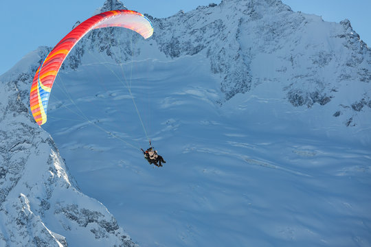 Para gliders fly on the background of high, snowy mountains. Red Para plane.