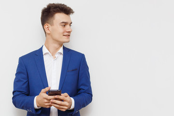 Young business man using his mobile device in business. Modern young guy with a phone in hand. Social networks business. Handsome man work on phone. Happy handsome guy browsing with his device.