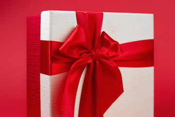 Pretty minimalist christmas gift box with ribbon isolated over red background.