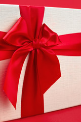 Pretty minimalist christmas gift box with ribbon isolated over red background.