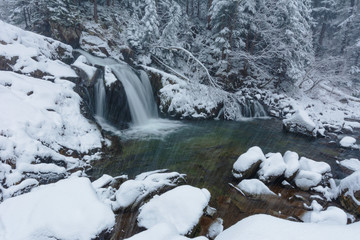 Waterfall in a snow-covered winter forest in the Ukrainian Carpathians.