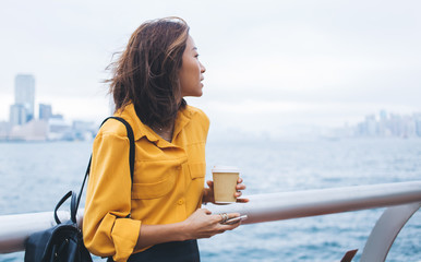 Dreamy Asian woman looking at seascape on windy day