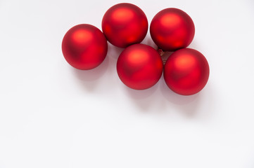 Five red Christmas baubles on a white background