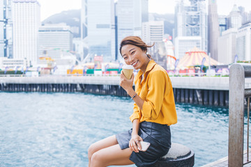 Fototapeta na wymiar Flirty Asian woman drinking coffee on mooring post