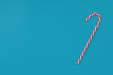 Creative christmas background. Striped candies on a blue background. Minimalistic scandy style. Empty space for text, top view, flat lay